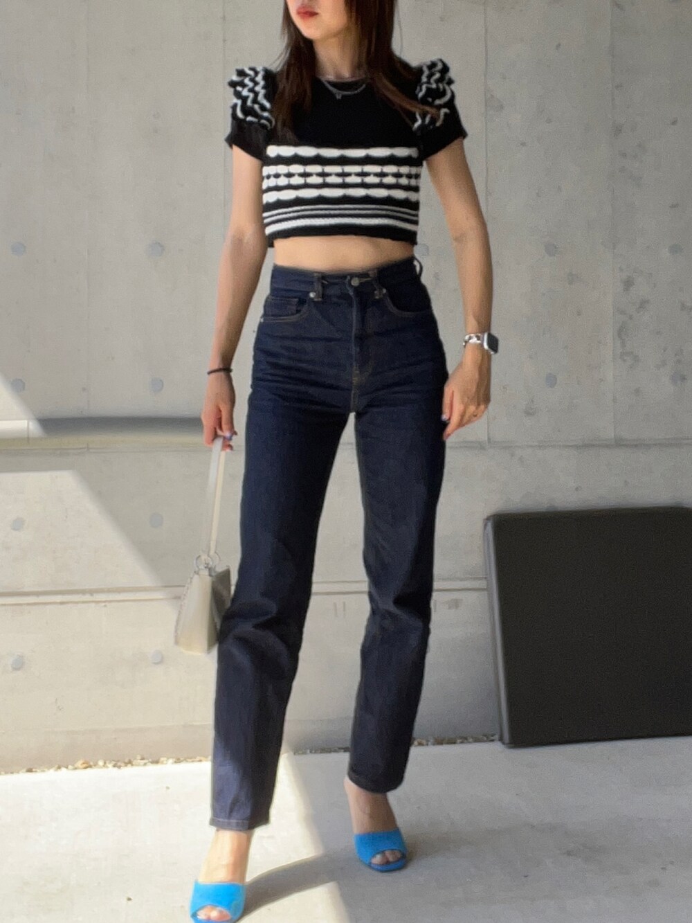 ブラック系のトップス、ブルー系のデニムパンツ、ブルー系のサンダルを着用したレディースの春コーディネートの2枚目の写真
