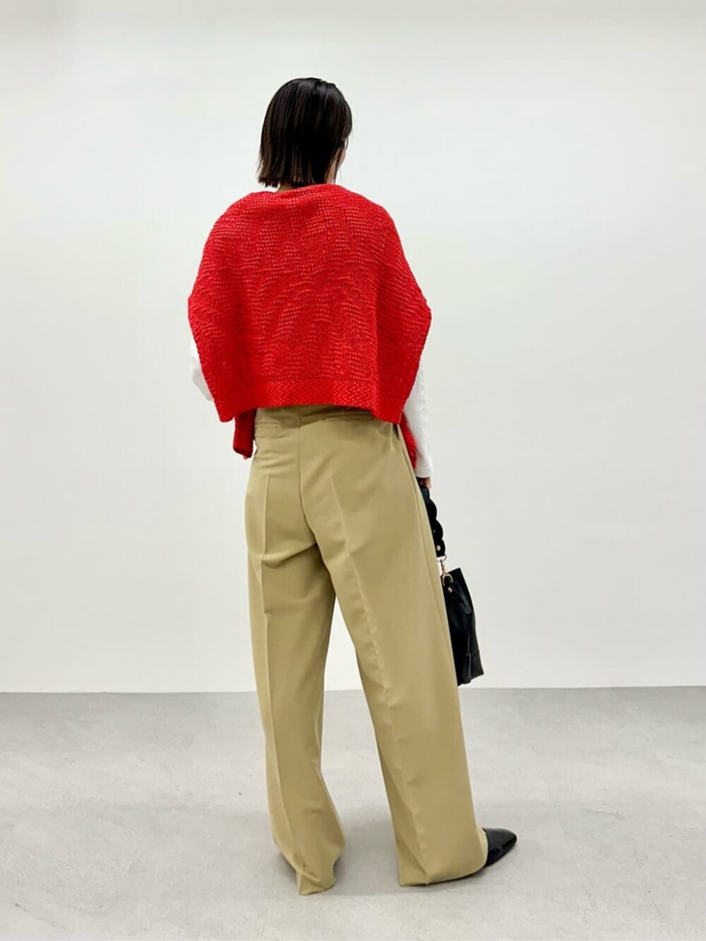 レッド系のニット/セーター、ホワイト系のTシャツ/カットソー、ベージュ系のその他パンツを着用したレディースの春コーディネートの3枚目の写真