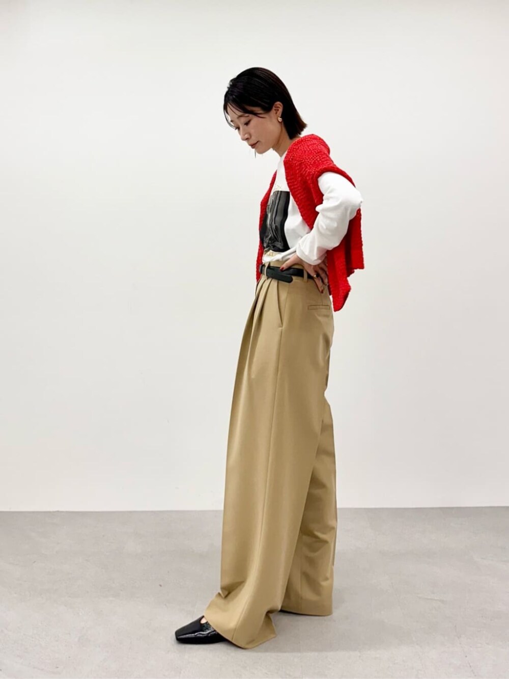 レッド系のニット/セーター、ホワイト系のTシャツ/カットソー、ベージュ系のその他パンツを着用したレディースの春コーディネートの4枚目の写真