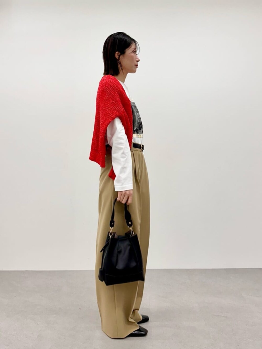 レッド系のニット/セーター、ホワイト系のTシャツ/カットソー、ベージュ系のその他パンツを着用したレディースの春コーディネートの2枚目の写真