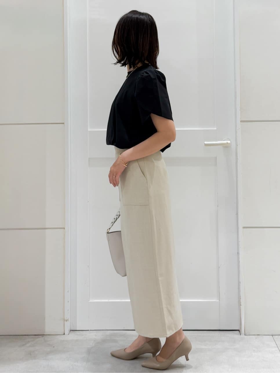 ブラック系のTシャツ/カットソー、ベージュ系のスカート、ホワイト系のショルダーバッグを着用したレディースの夏コーディネートの7枚目の写真