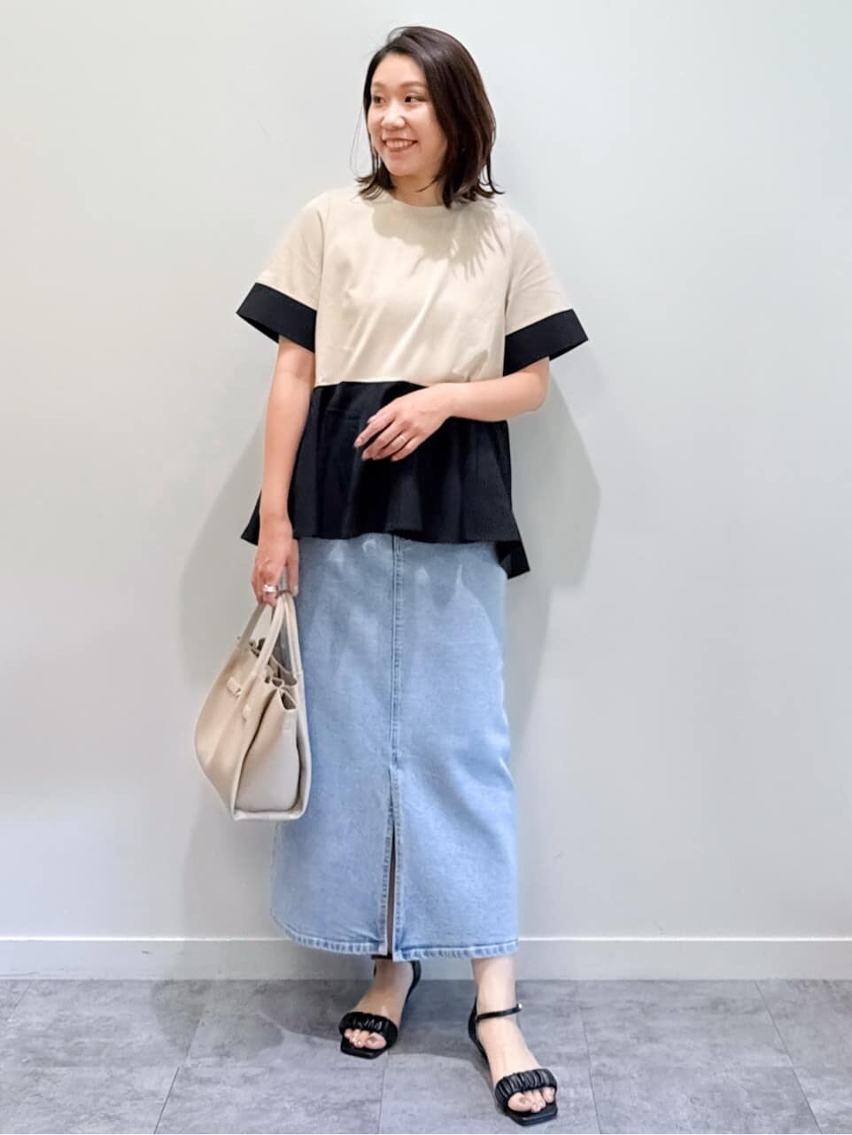 ベージュ系のTシャツ/カットソー、ブルー系のデニムスカート、ベージュ系のショルダーバッグを着用したレディースの夏コーディネートの6枚目の写真