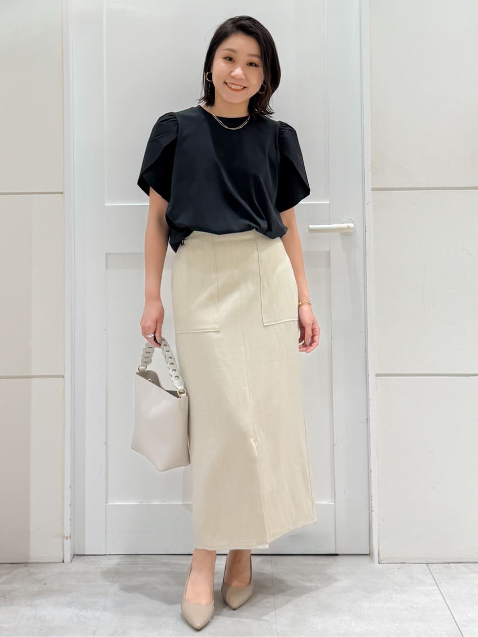 ブラック系のTシャツ/カットソー、ベージュ系のスカート、ホワイト系のショルダーバッグを着用したレディースの夏コーディネートの5枚目の写真