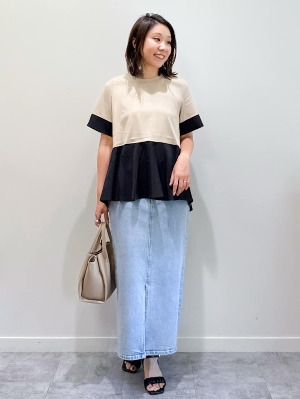 ベージュ系のTシャツ/カットソー、ブルー系のデニムスカート、ベージュ系のショルダーバッグを着用したレディースの夏コーディネートの3枚目の写真