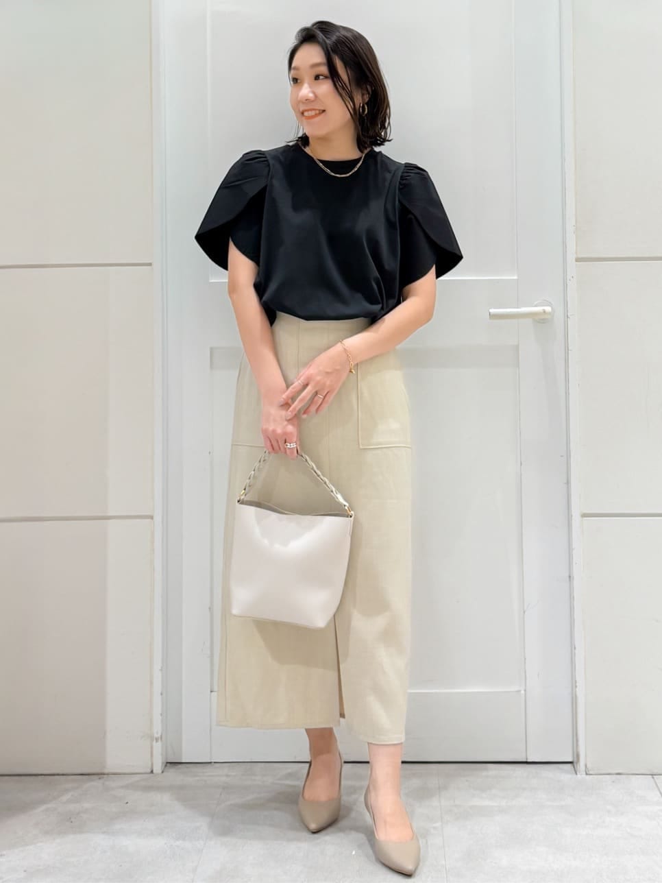 ブラック系のTシャツ/カットソー、ベージュ系のスカート、ホワイト系のショルダーバッグを着用したレディースの夏コーディネートの4枚目の写真