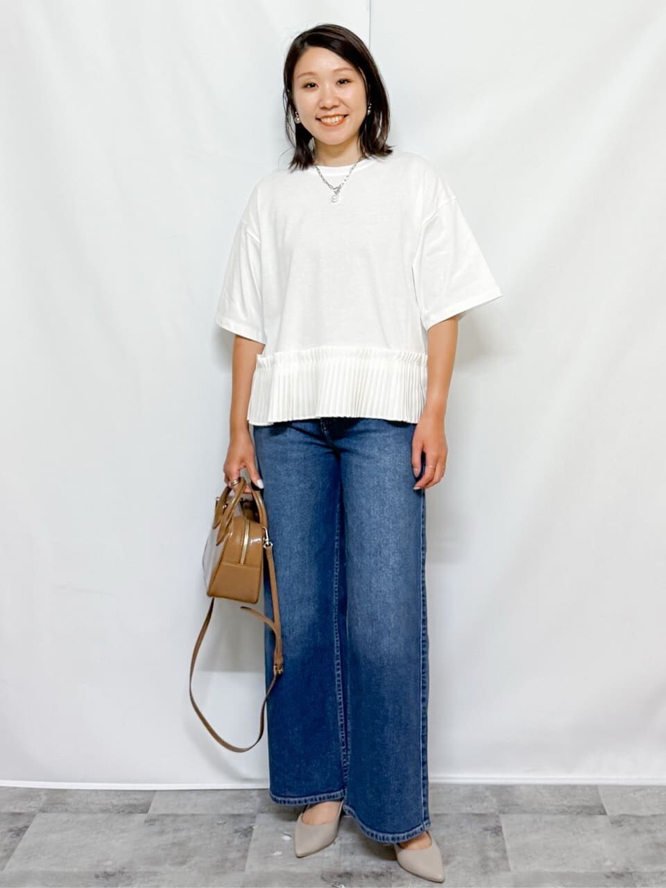 ホワイト系のTシャツ/カットソー、ブルー系のデニムパンツ、ベージュ系のショルダーバッグを着用したレディースの夏コーディネートの2枚目の写真