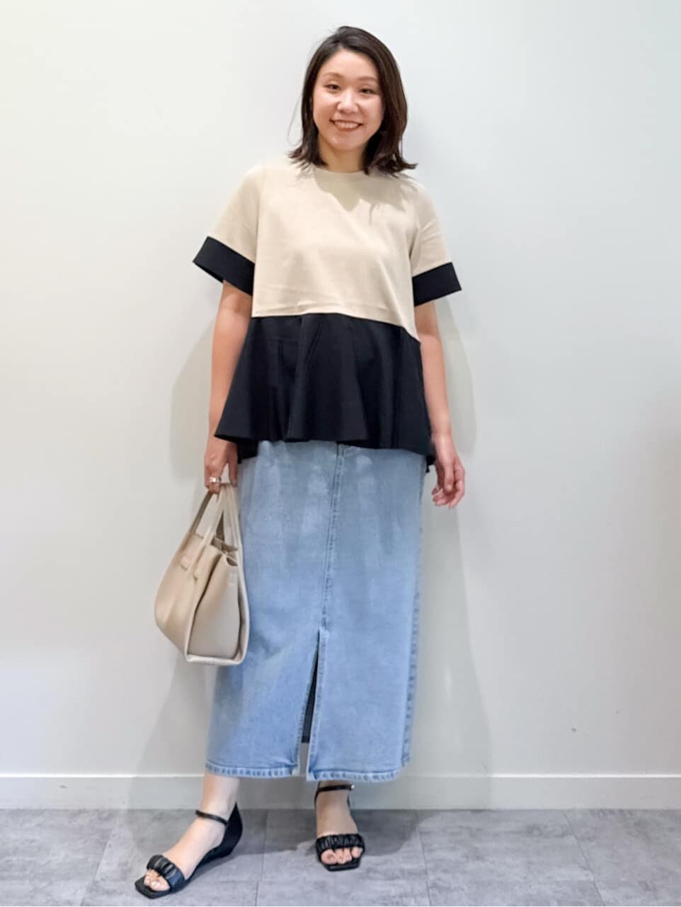 ベージュ系のTシャツ/カットソー、ブルー系のデニムスカート、ベージュ系のショルダーバッグを着用したレディースの夏コーディネートの2枚目の写真