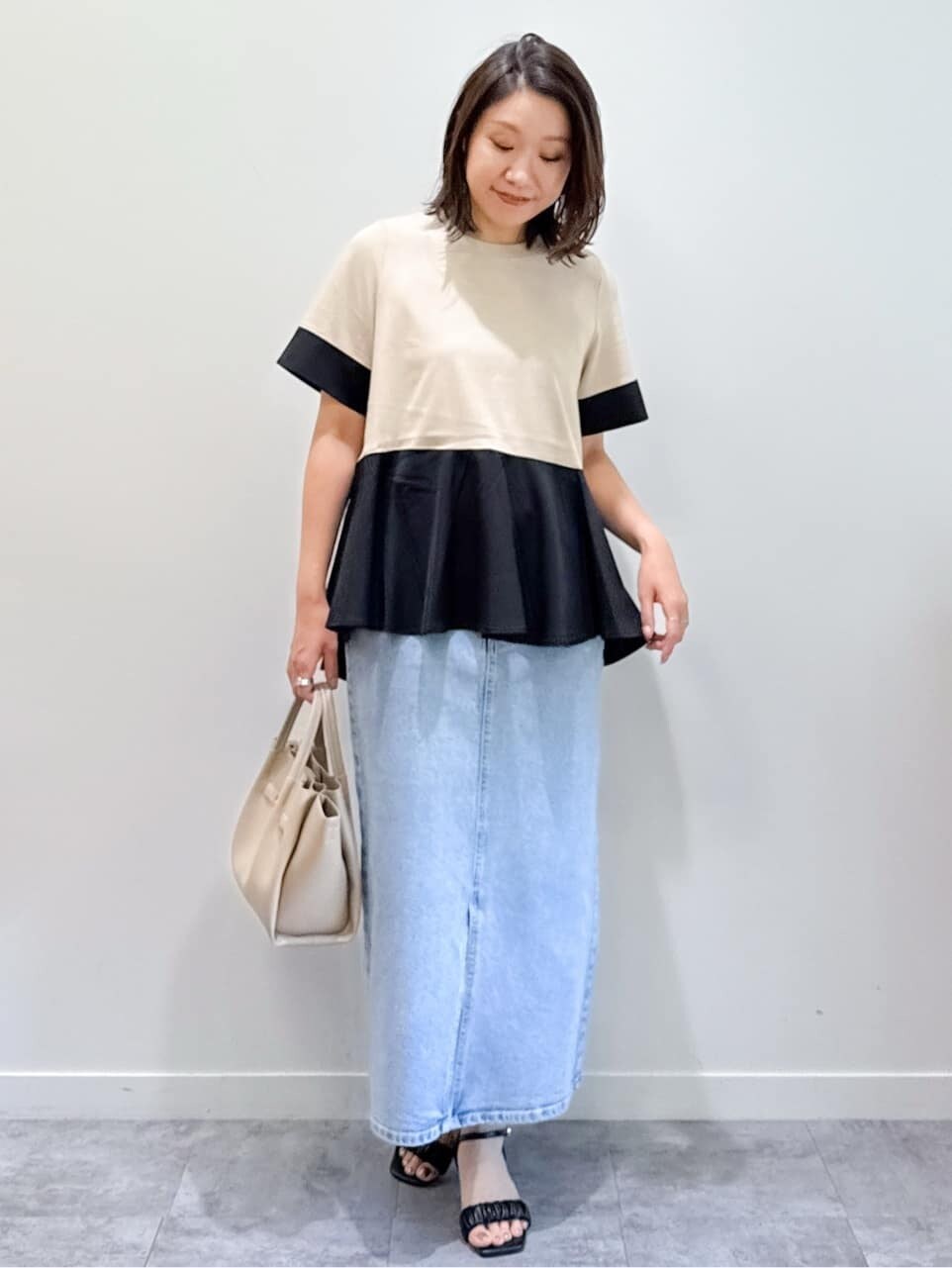 ベージュ系のTシャツ/カットソー、ブルー系のデニムスカート、ベージュ系のショルダーバッグを着用したレディースの夏コーディネートの5枚目の写真