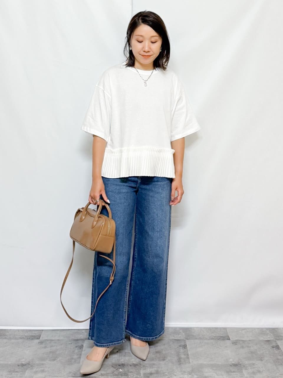 ホワイト系のTシャツ/カットソー、ブルー系のデニムパンツ、ベージュ系のショルダーバッグを着用したレディースの夏コーディネートの3枚目の写真