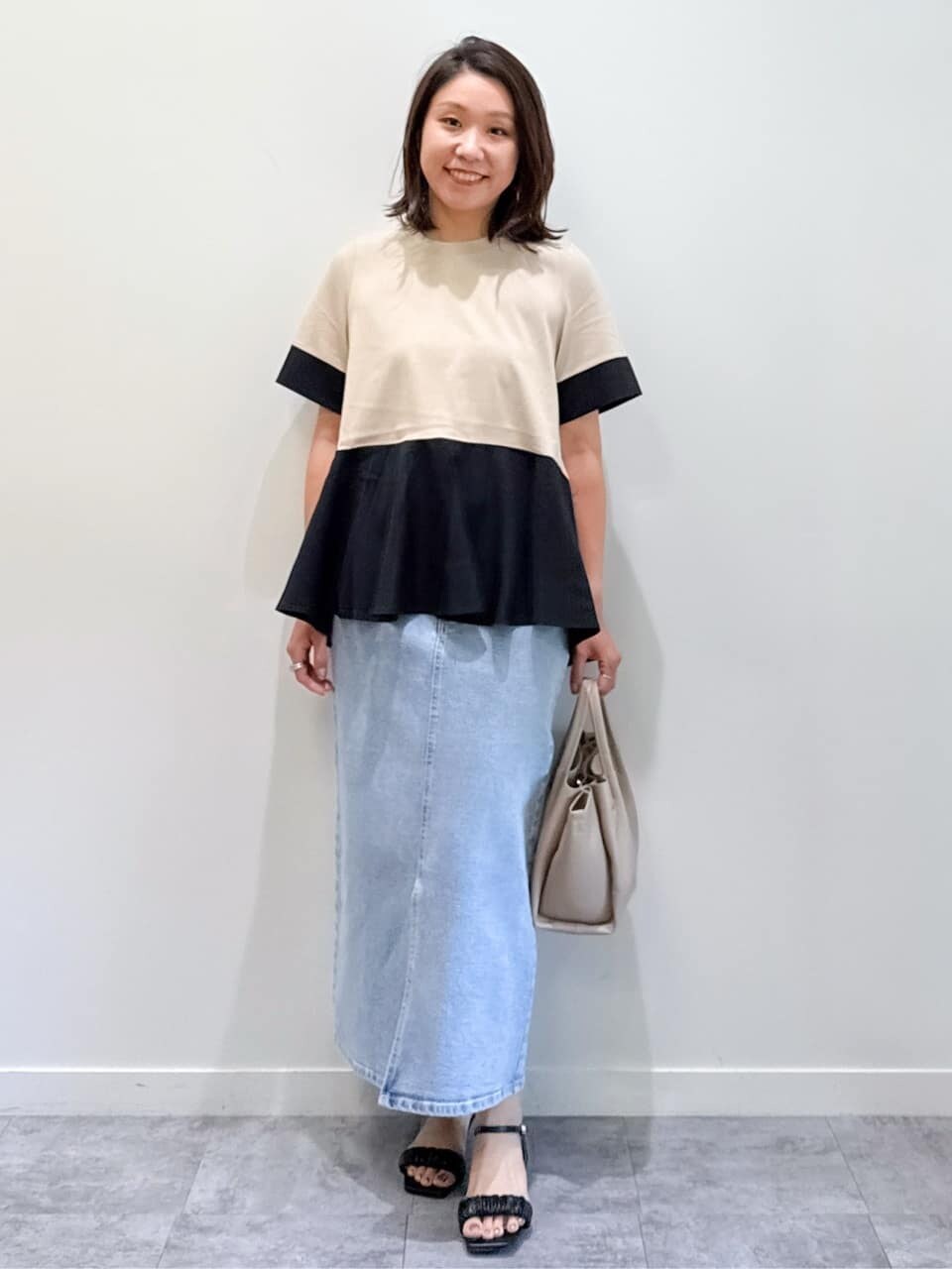 ベージュ系のTシャツ/カットソー、ブルー系のデニムスカート、ベージュ系のショルダーバッグを着用したレディースの夏コーディネートの4枚目の写真