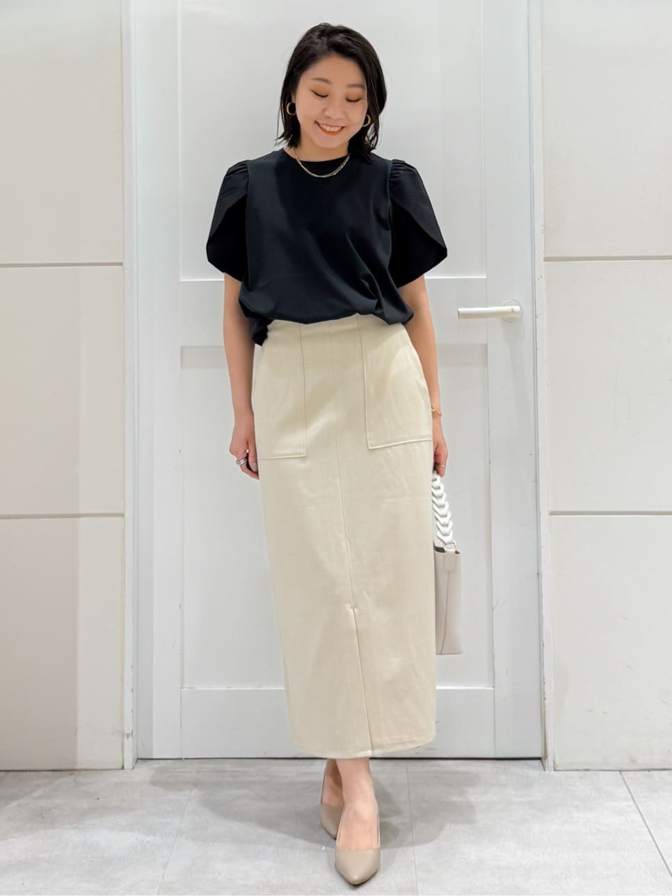 ブラック系のTシャツ/カットソー、ベージュ系のスカート、ホワイト系のショルダーバッグを着用したレディースの夏コーディネートの3枚目の写真