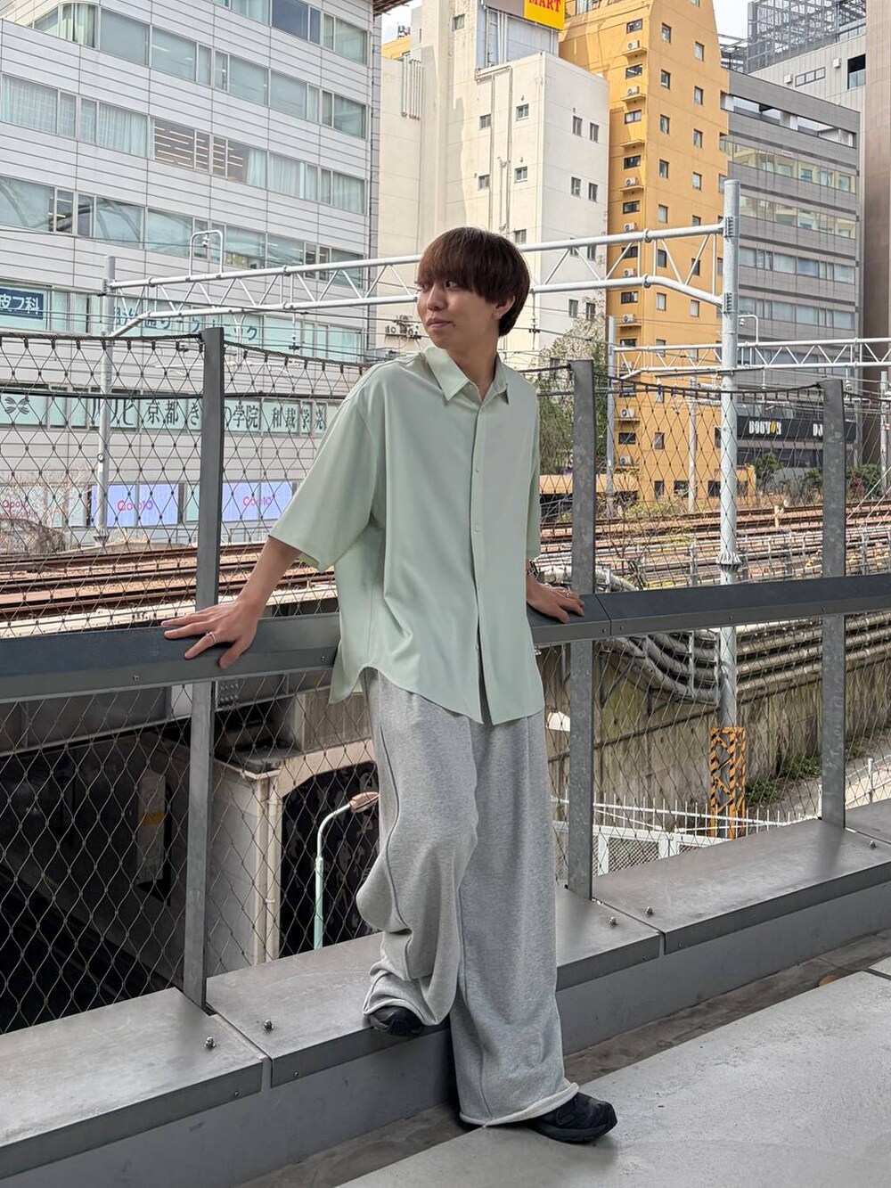 グリーン系のシャツ/ブラウス、ブラック系のスニーカー、グレー系のスウェットパンツを着用したメンズの春コーディネートの2枚目の写真