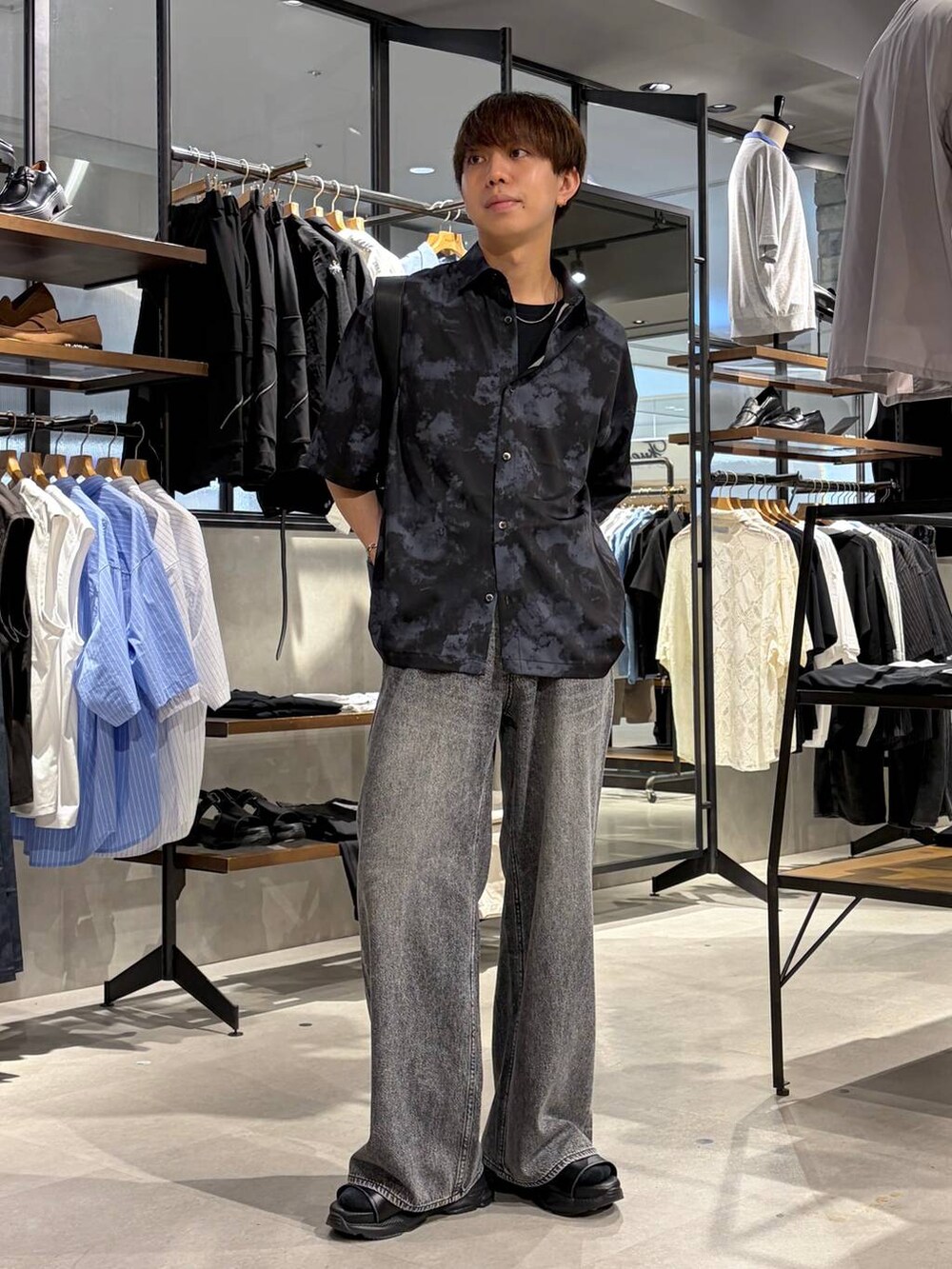 ブラック系のTシャツ/カットソー、グレー系のデニムパンツ、ブラック系のサンダルを着用したメンズの夏コーディネートの2枚目の写真
