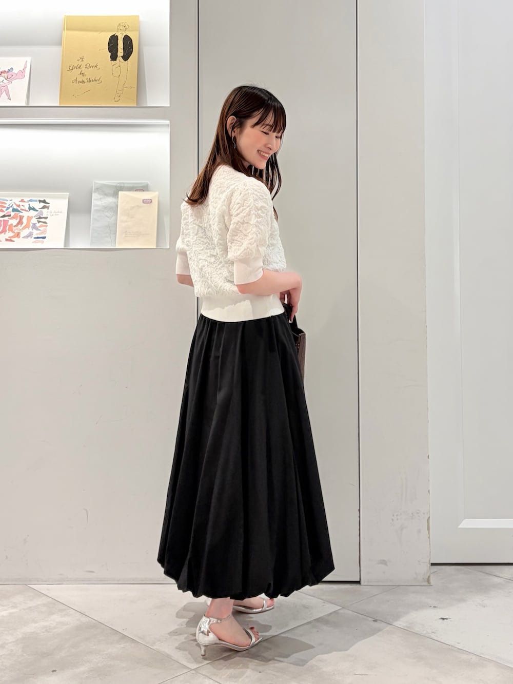 ブラック系のスカート、ホワイト系のカーディガン/ボレロ、ブラウン系のショルダーバッグを着用したレディースの夏コーディネートの3枚目の写真