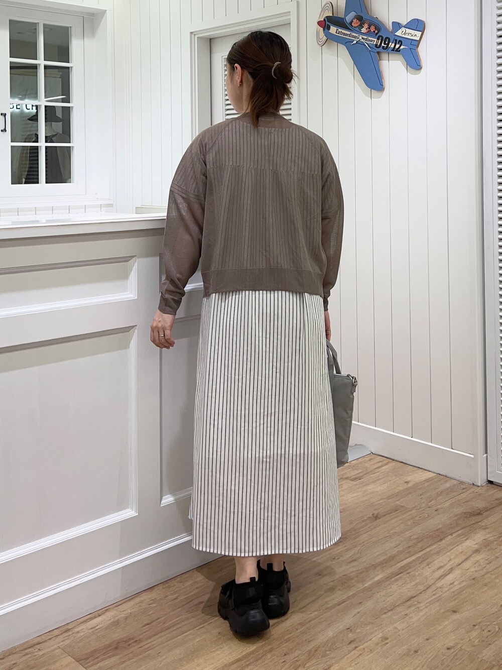 ブラウン系のカーディガン/ボレロ、ホワイト系のワンピース、ブラック系のサンダルを着用したレディースの春コーディネートの2枚目の写真