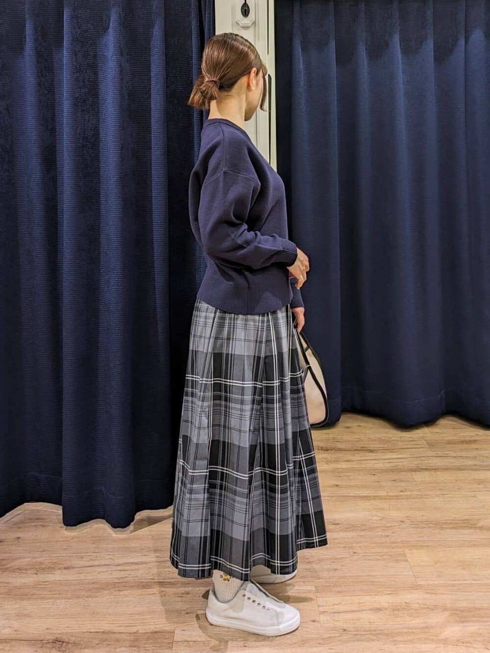 ブルー系のニット/セーター、グリーン系のスカート、ブラック系のショルダーバッグを着用したレディースの春コーディネートの2枚目の写真