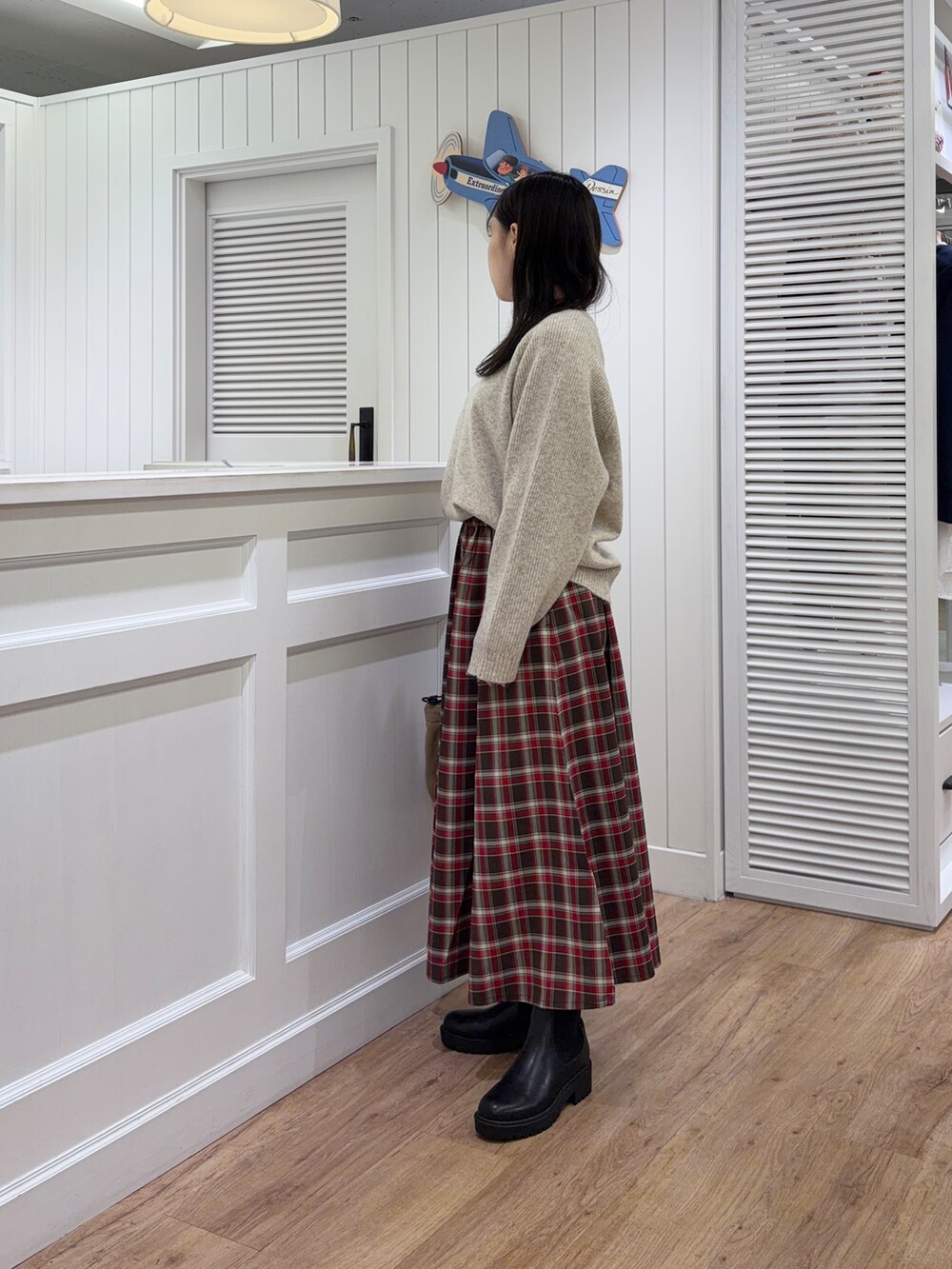 ベージュ系のニット/セーター、レッド系のスカート、ベージュ系のトートバッグを着用したレディースの秋コーディネートの2枚目の写真