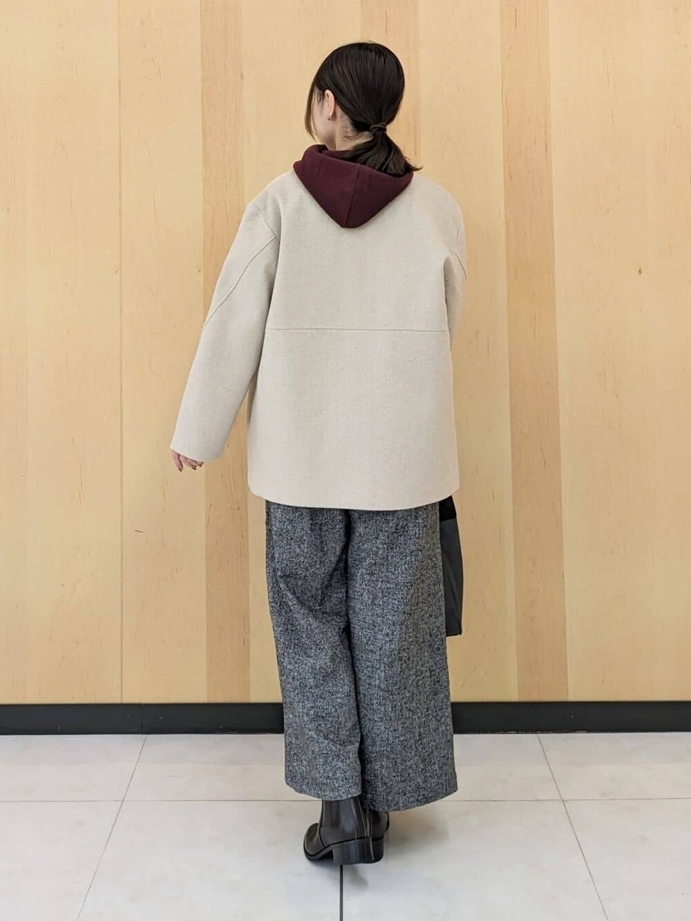 ベージュ系のノーカラーコート、ブラック系のニット/セーター、レッド系のニット/セーターを着用したレディースの冬コーディネートの3枚目の写真