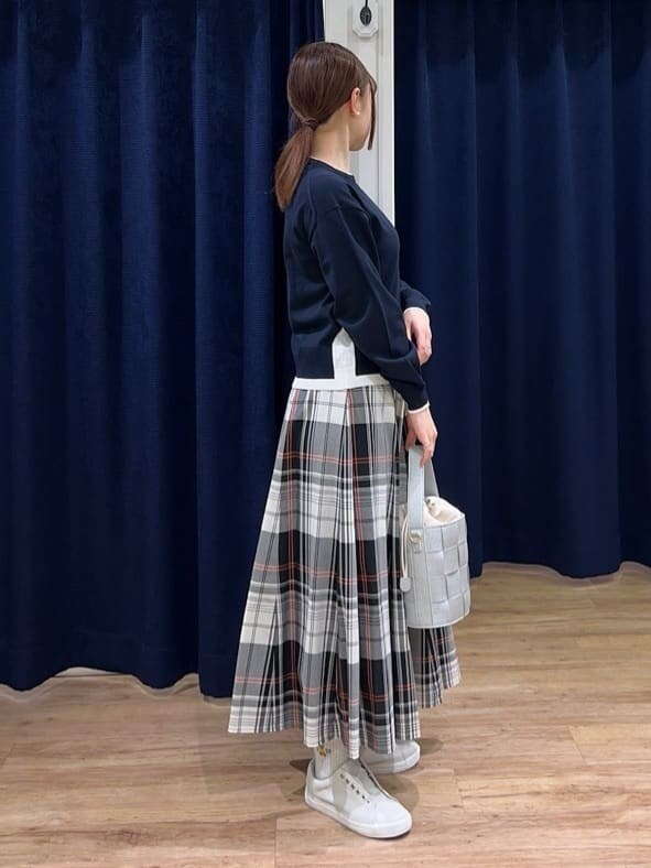 ブルー系のニット/セーター、レッド系のスカート、シルバー系のショルダーバッグを着用したレディースの春コーディネートの2枚目の写真