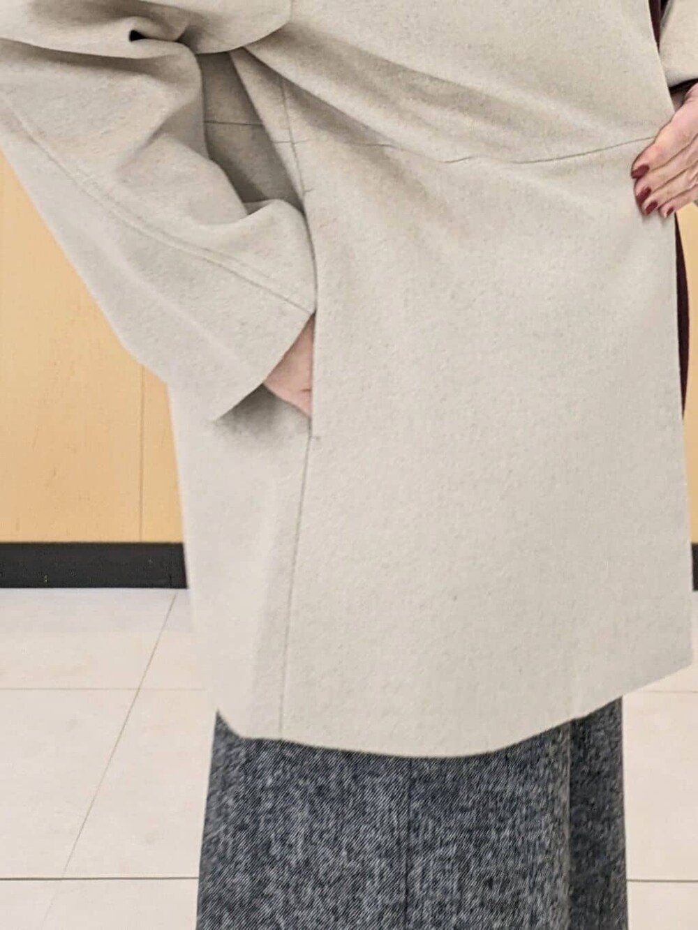 ベージュ系のノーカラーコート、ブラック系のニット/セーター、レッド系のニット/セーターを着用したレディースの冬コーディネートの6枚目の写真
