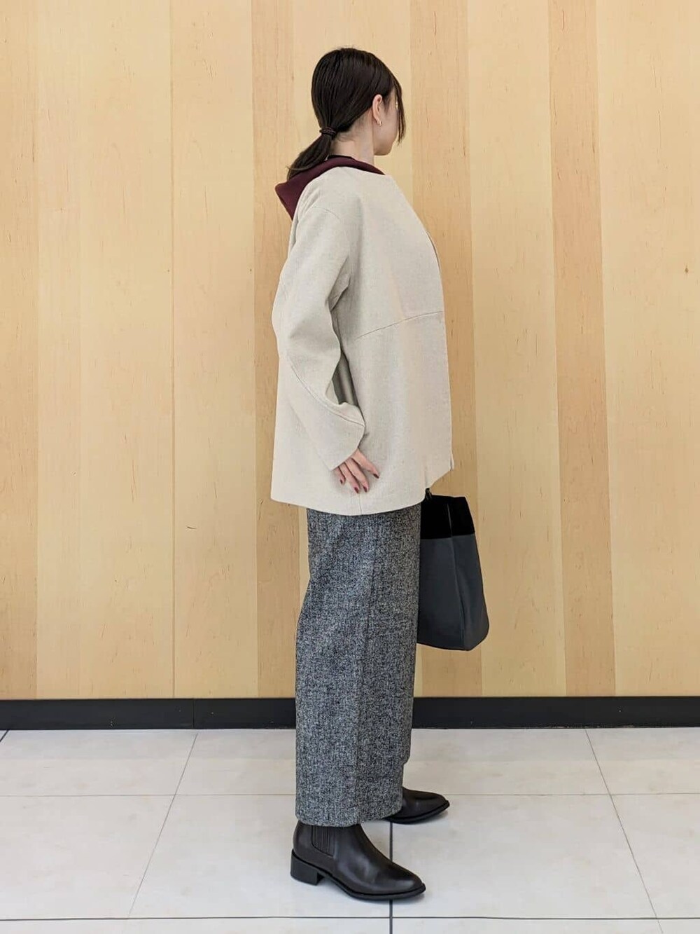 ベージュ系のノーカラーコート、ブラック系のニット/セーター、レッド系のニット/セーターを着用したレディースの冬コーディネートの2枚目の写真
