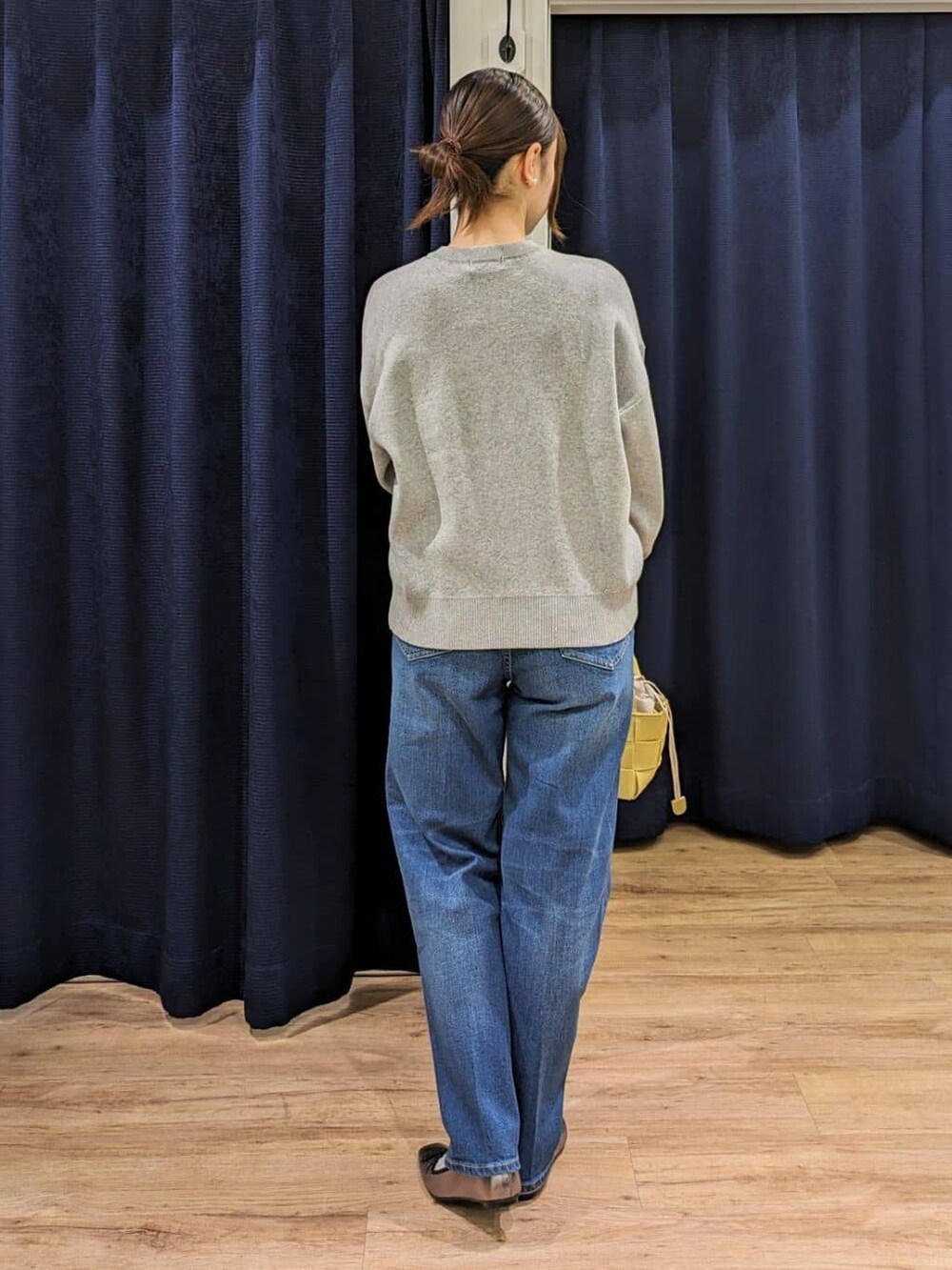 グレー系のニット/セーター、ブルー系のデニムパンツ、イエロー系のトートバッグを着用したレディースの冬コーディネートの3枚目の写真