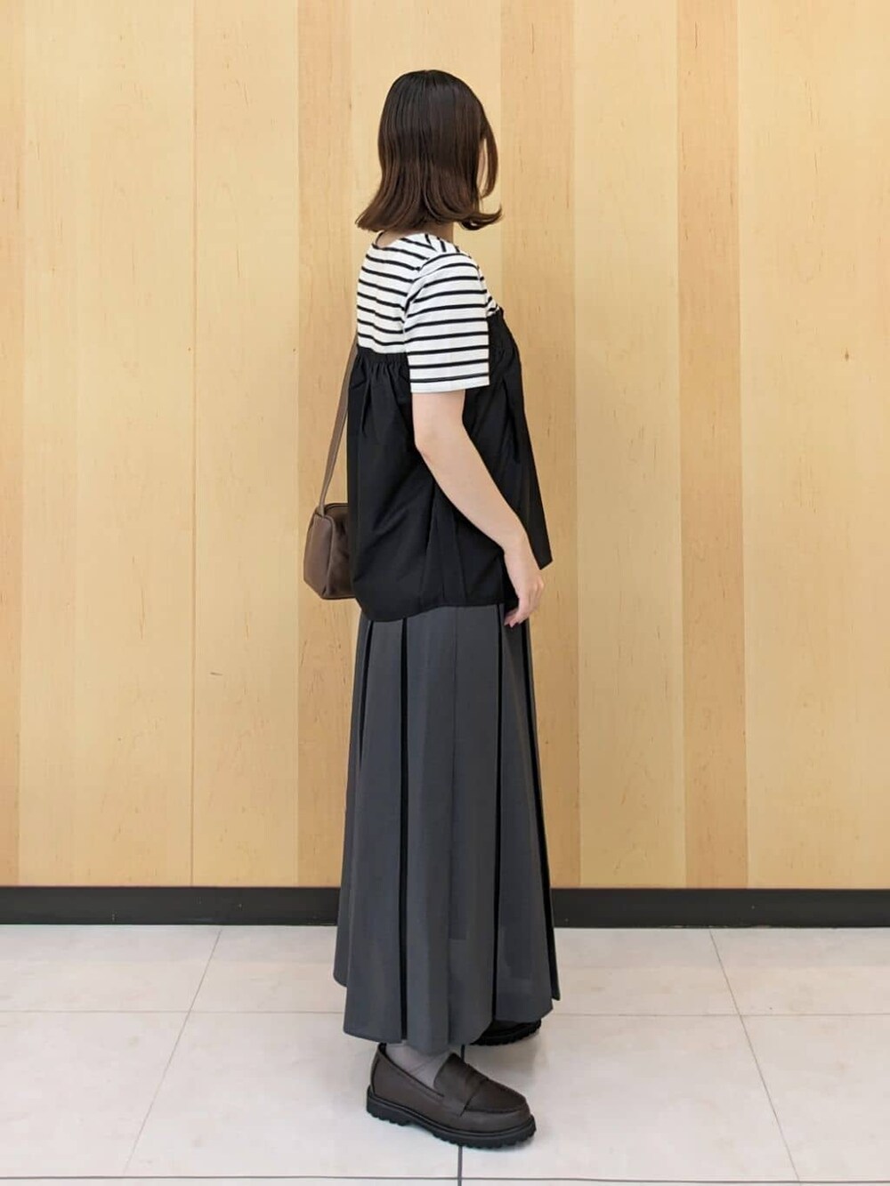 ブラック系のTシャツ/カットソー、グレー系のスカート、ブラウン系のショルダーバッグを着用したレディースの秋コーディネートの2枚目の写真