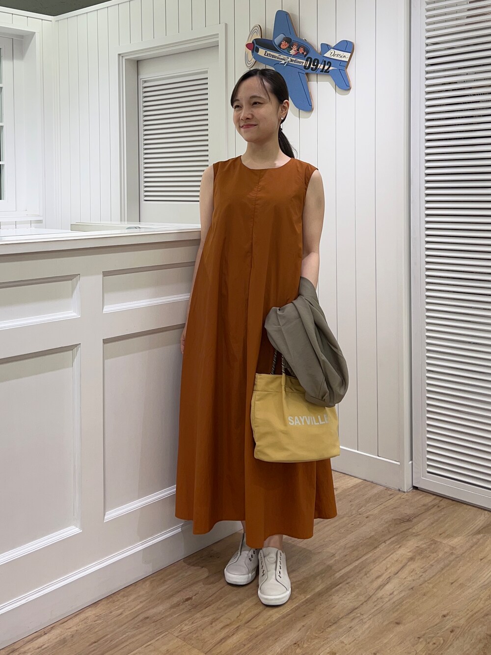 グリーン系のブルゾン、イエロー系のワンピース、イエロー系のトートバッグを着用したレディースの夏コーディネートの8枚目の写真