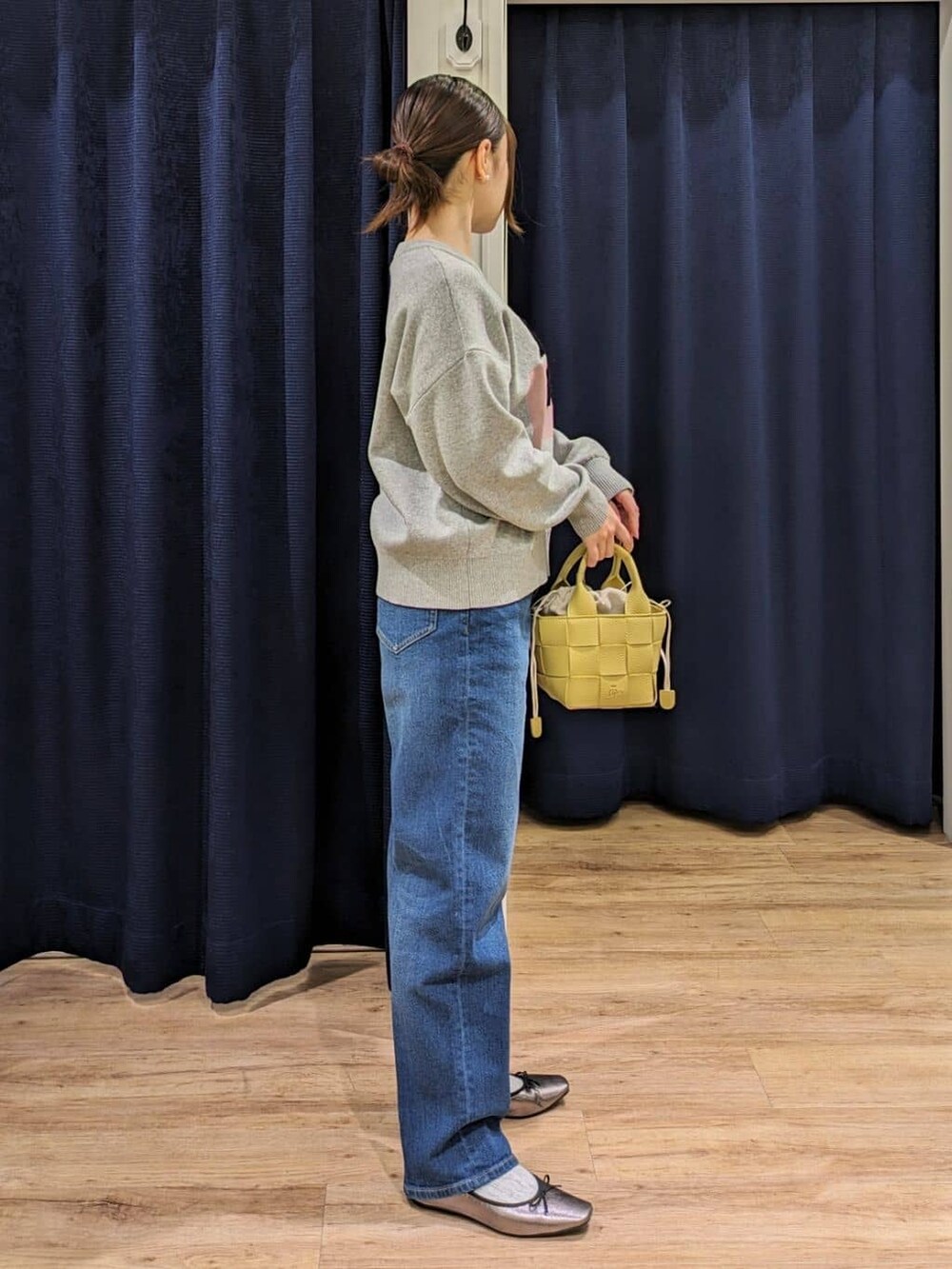 グレー系のニット/セーター、ブルー系のデニムパンツ、イエロー系のトートバッグを着用したレディースの冬コーディネートの2枚目の写真