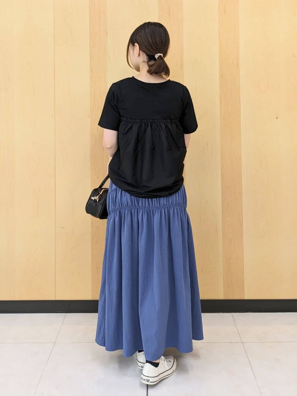 ブラック系のTシャツ/カットソー、ブルー系のスカート、ブラック系のショルダーバッグを着用したレディースの秋コーディネートの3枚目の写真