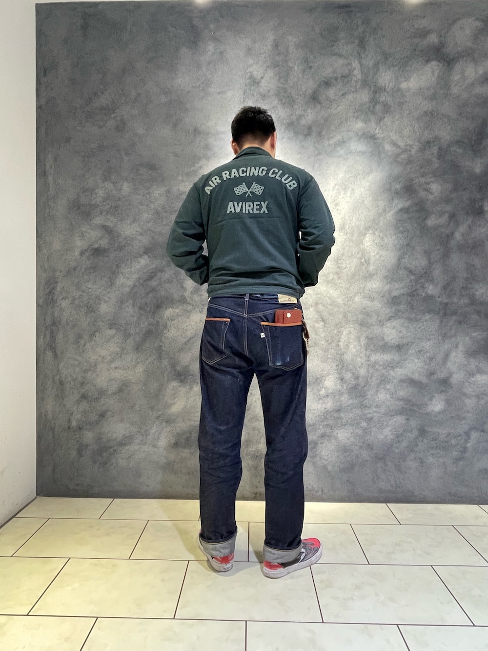 グリーン系のブルゾン、ブラウン系のデニムパンツを着用したメンズの秋コーディネートの2枚目の写真