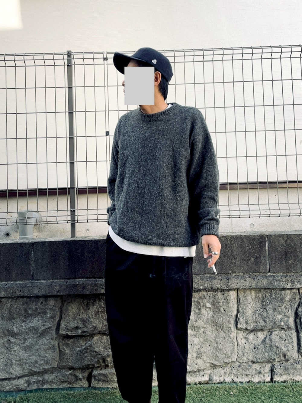 グレー系のニット/セーター、ブラック系のチノパンツ、ブルー系のキャップを着用したメンズの秋コーディネートの2枚目の写真