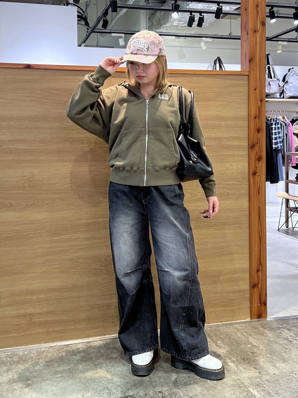 グリーン系のパーカー、ブラック系のデニムパンツ、ブラック系のショルダーバッグを着用したレディースの春コーディネートの2枚目の写真