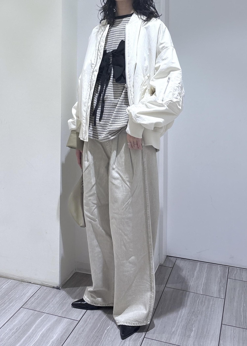 ブラック系のパンプス、ブラック系のベスト、ホワイト系のMA-1を着用したレディースの冬コーディネートの2枚目の写真