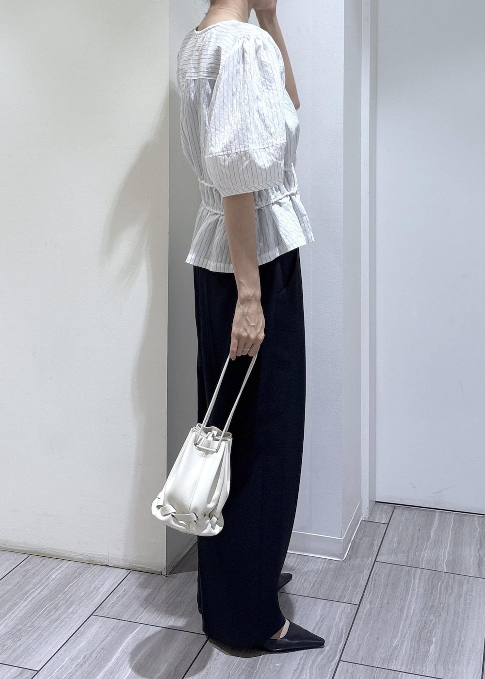 ブラック系のパンプス、ブラック系のショルダーバッグ、ホワイト系のシャツ/ブラウスを着用したレディースの春コーディネートの6枚目の写真