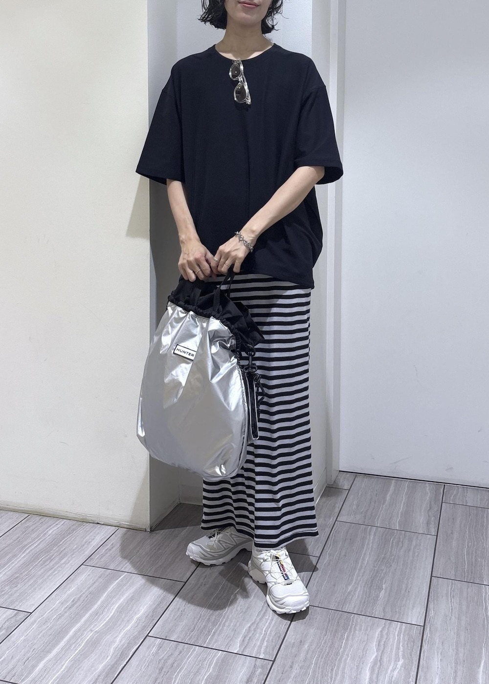 ブルー系のスカート、シルバー系のトートバッグ、ブルー系のTシャツ/カットソーを着用したレディースの夏コーディネートの2枚目の写真