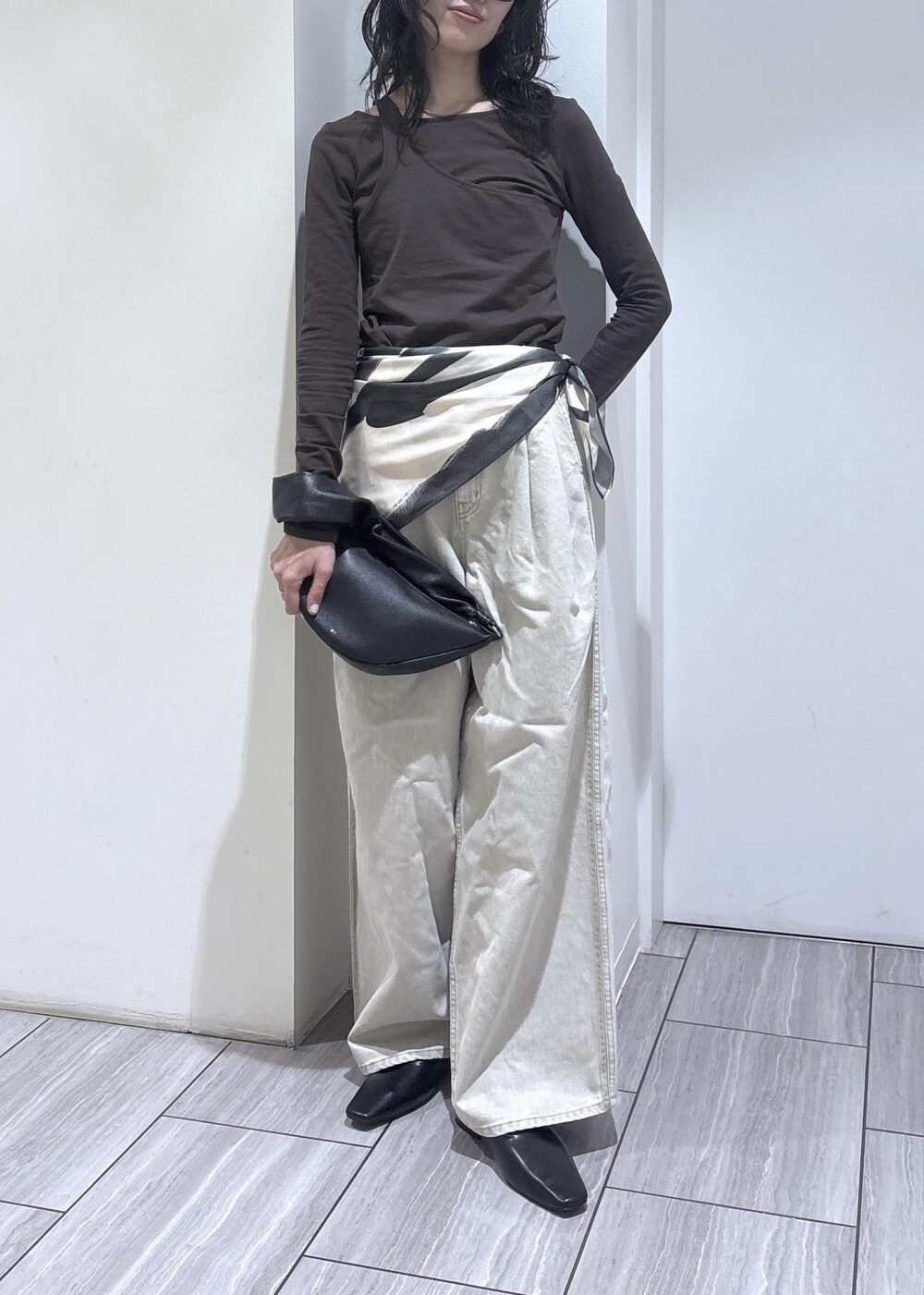 ブラウン系のTシャツ/カットソー、ブラック系のサンダル、ベージュ系のデニムパンツを着用したレディースの冬コーディネートの2枚目の写真