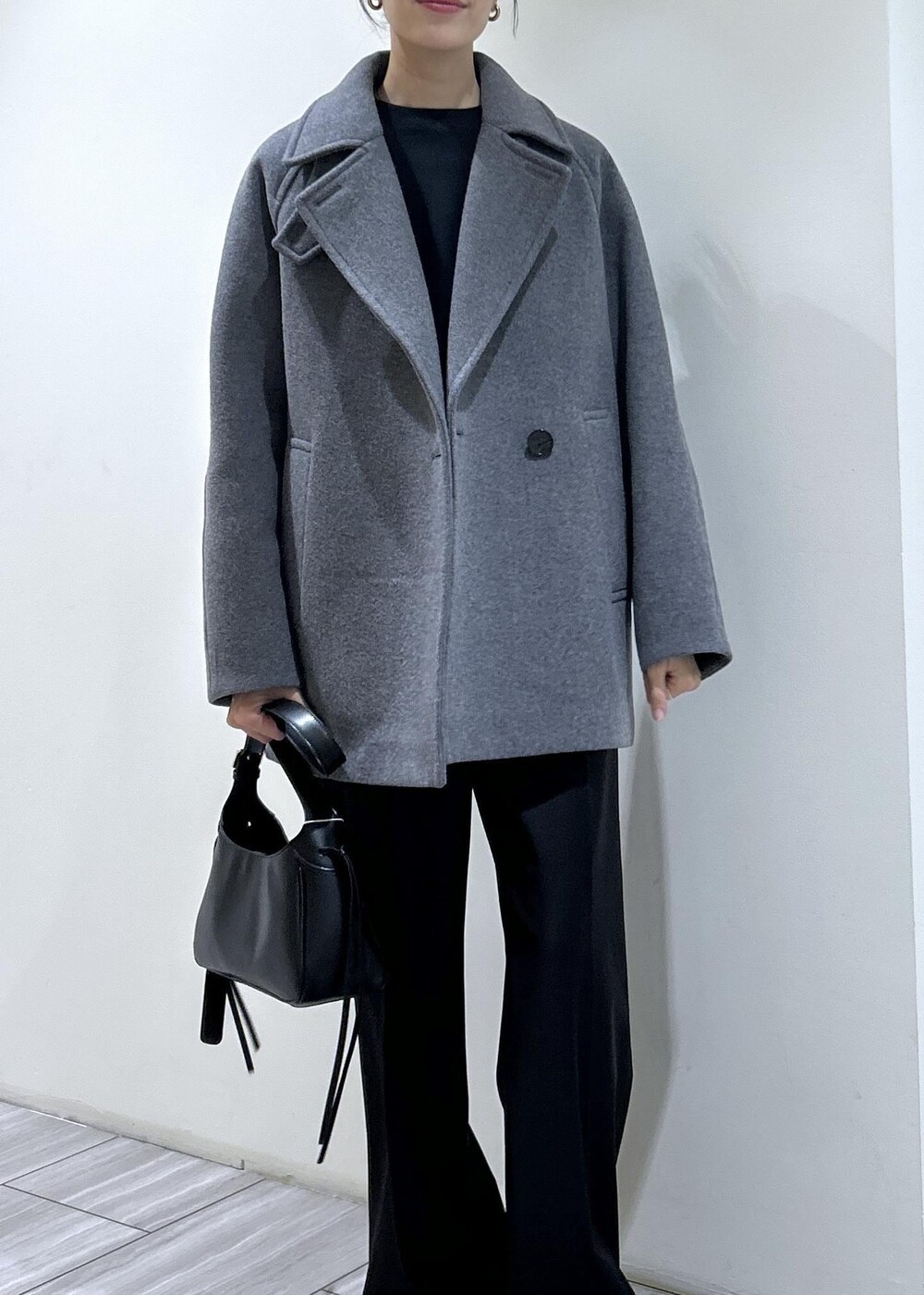 ブラック系のスウェット、ブラック系のショルダーバッグ、グレー系のステンカラーコートを着用したレディースの秋コーディネートの3枚目の写真