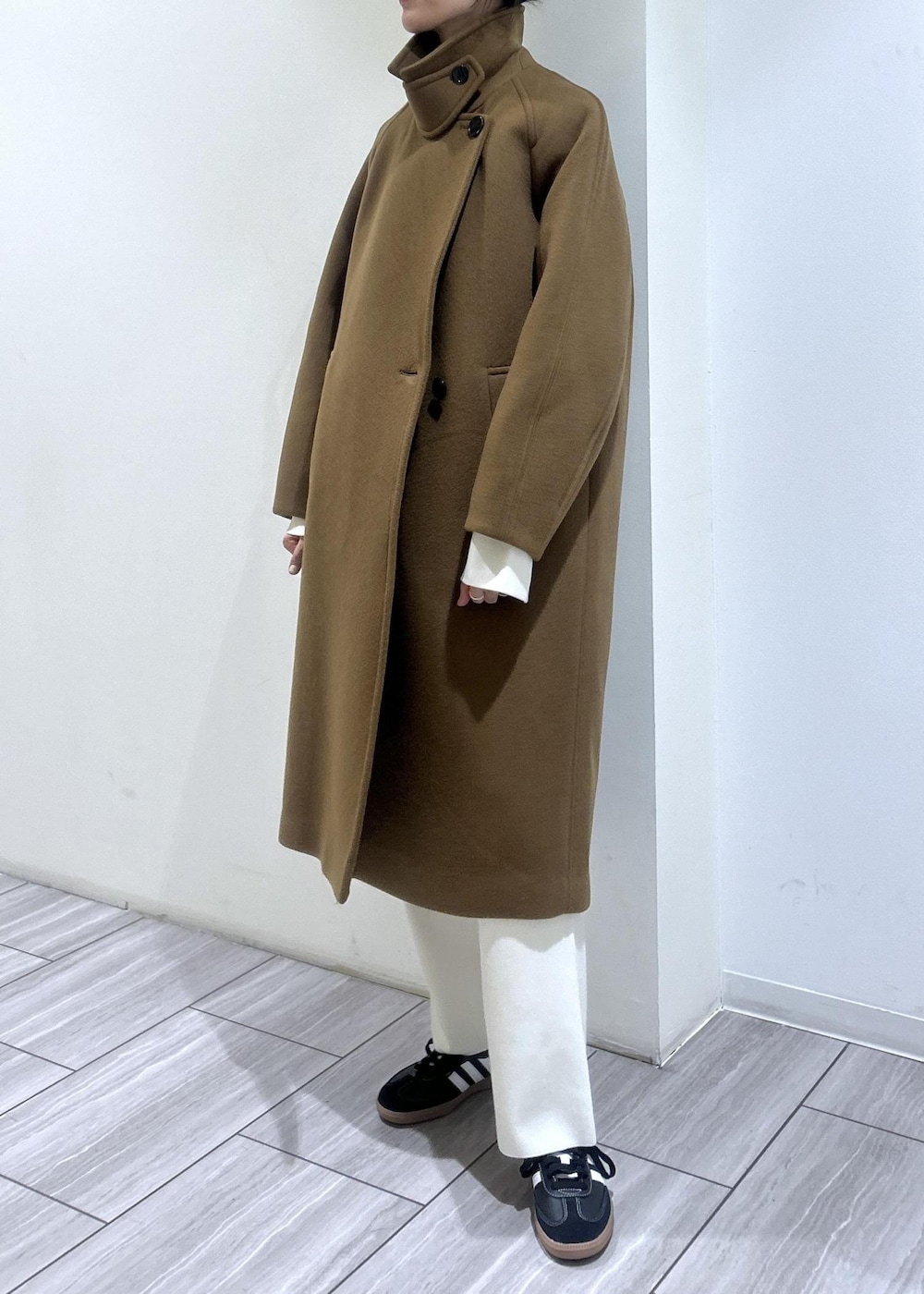 イエロー系のステンカラーコート、ホワイト系のニット/セーター、ホワイト系のその他パンツを着用したレディースの秋コーディネートの6枚目の写真