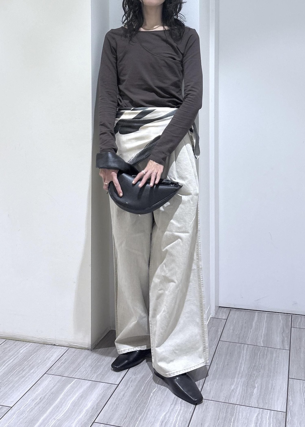 ブラウン系のTシャツ/カットソー、ブラック系のサンダル、ベージュ系のデニムパンツを着用したレディースの冬コーディネートの4枚目の写真