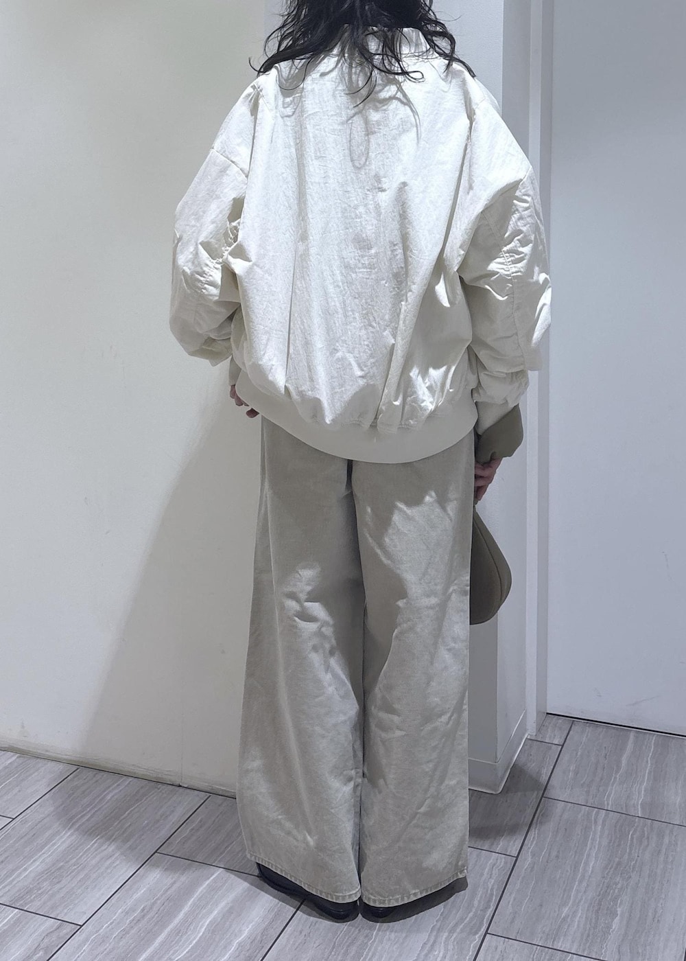 ブラック系のパンプス、ブラック系のベスト、ホワイト系のMA-1を着用したレディースの冬コーディネートの3枚目の写真