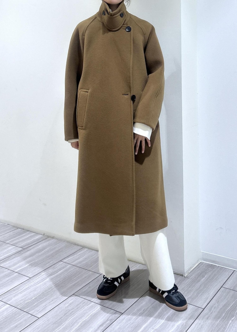 イエロー系のステンカラーコート、ホワイト系のニット/セーター、ホワイト系のその他パンツを着用したレディースの秋コーディネートの5枚目の写真