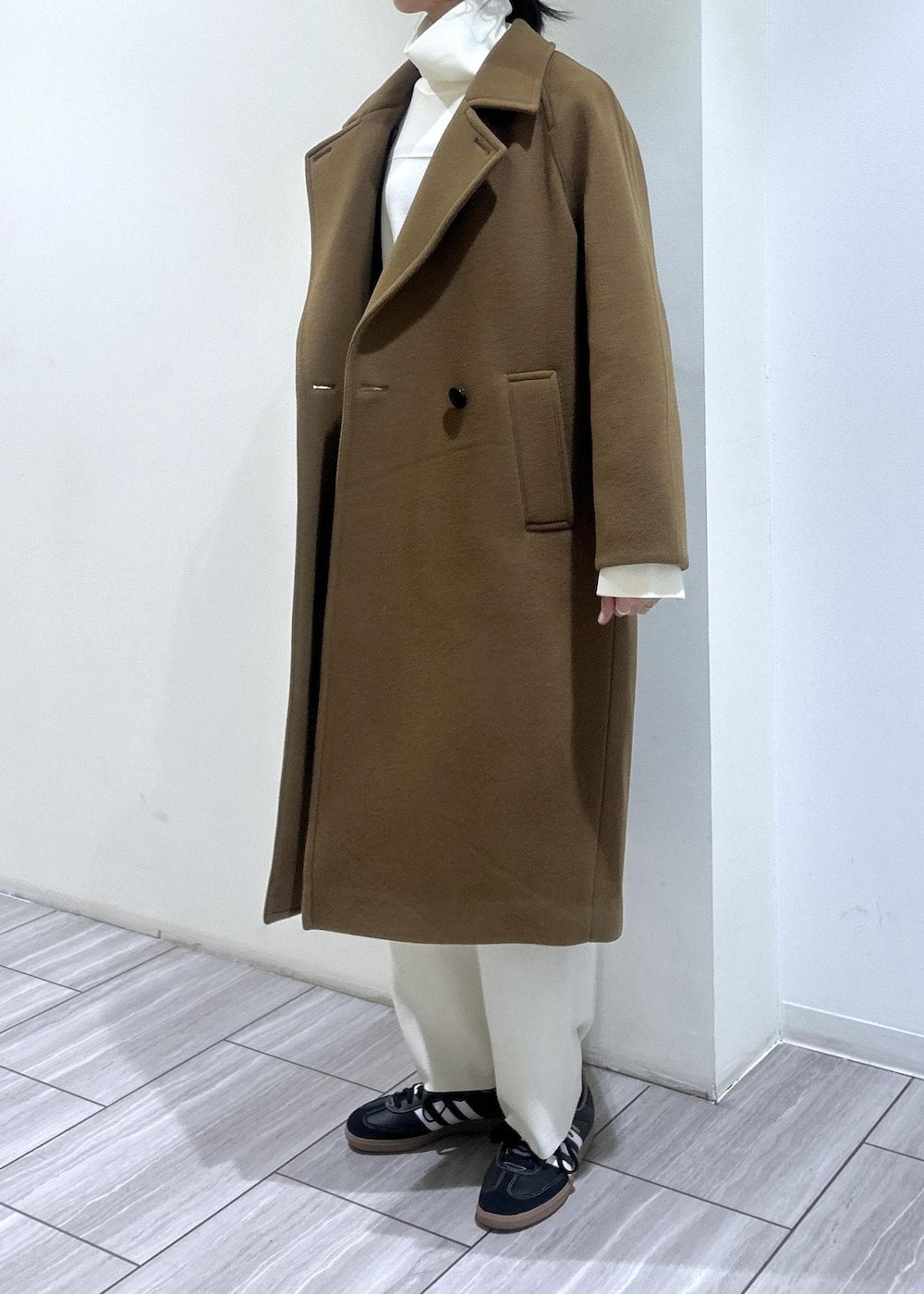 イエロー系のステンカラーコート、ホワイト系のニット/セーター、ホワイト系のその他パンツを着用したレディースの秋コーディネートの3枚目の写真