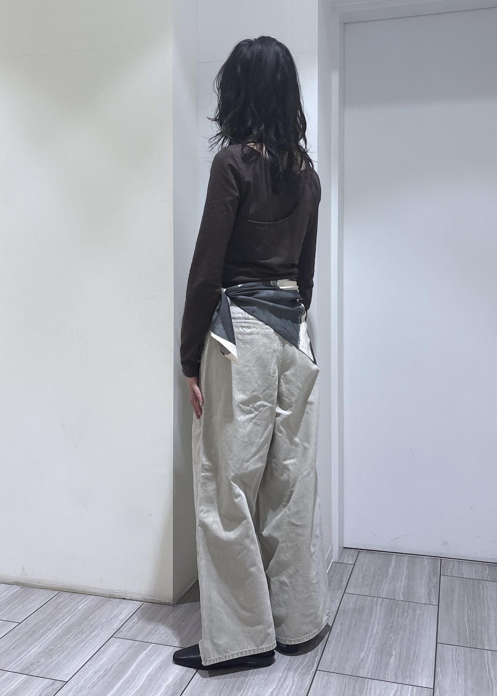 ブラウン系のTシャツ/カットソー、ブラック系のサンダル、ベージュ系のデニムパンツを着用したレディースの冬コーディネートの3枚目の写真