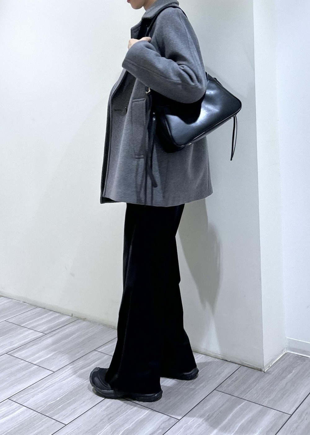 ブラック系のスウェット、ブラック系のショルダーバッグ、グレー系のステンカラーコートを着用したレディースの秋コーディネートの4枚目の写真