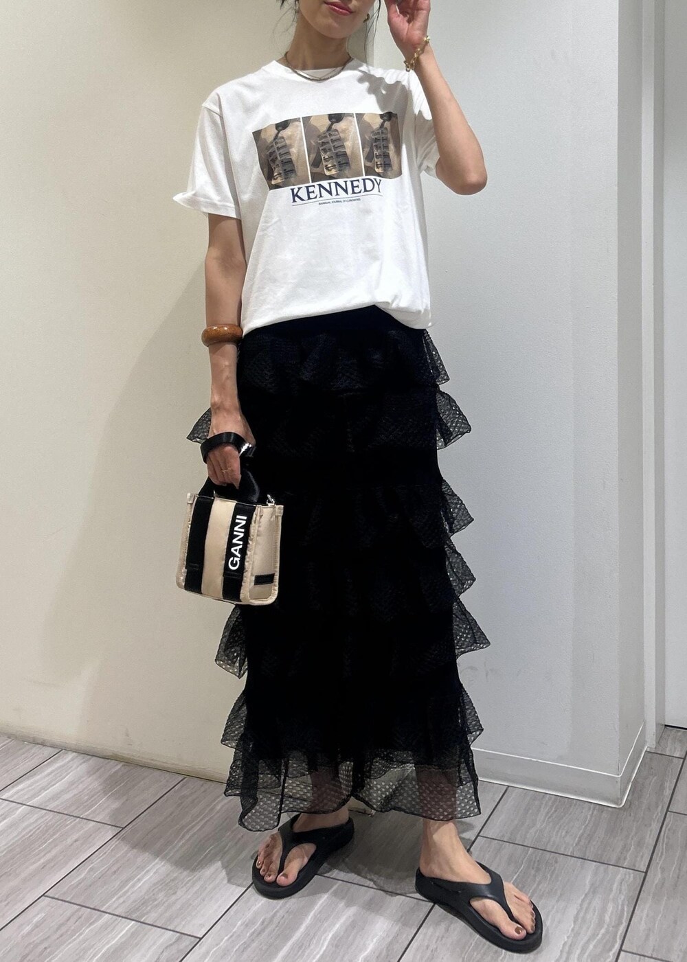 ブラック系のサンダル、ホワイト系のTシャツ/カットソー、ブラック系のスカートを着用したレディースの夏コーディネートの2枚目の写真