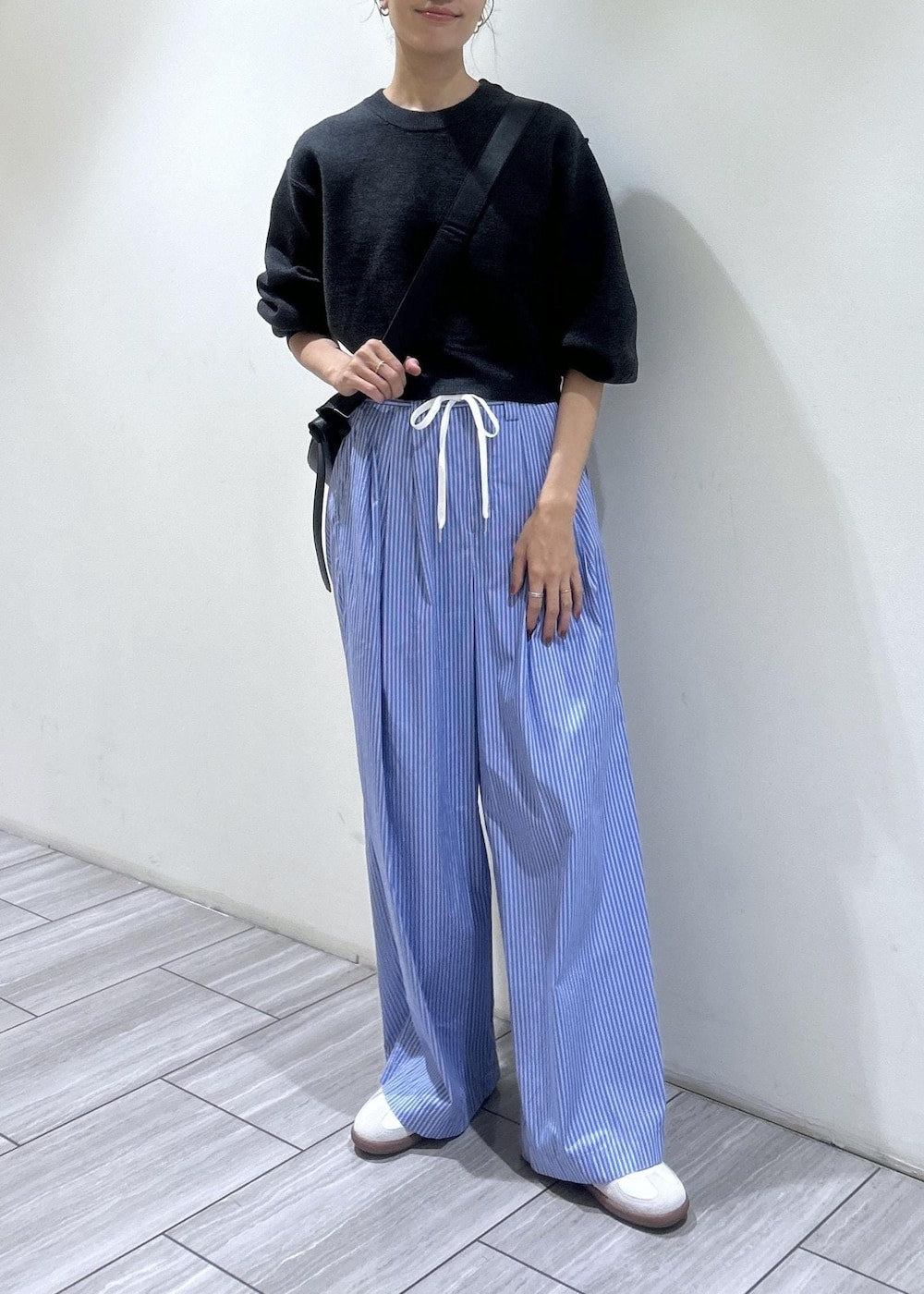 ブラック系のショルダーバッグ、ブルー系のスラックス、ホワイト系のスニーカーを着用したレディースの秋コーディネートの5枚目の写真