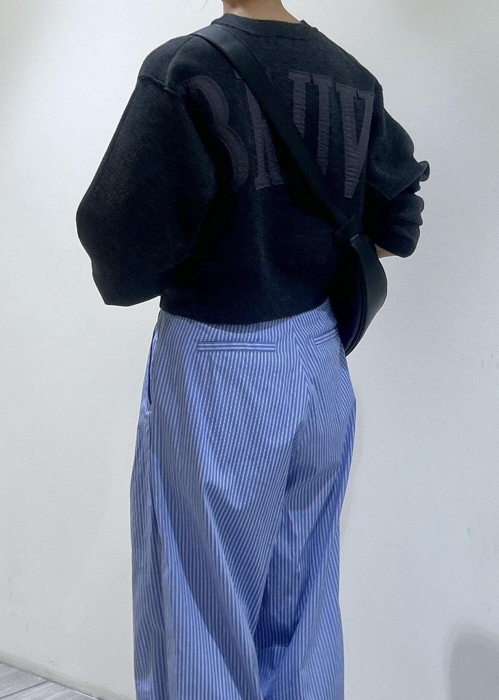 ブラック系のショルダーバッグ、ブルー系のスラックス、ホワイト系のスニーカーを着用したレディースの秋コーディネートの3枚目の写真