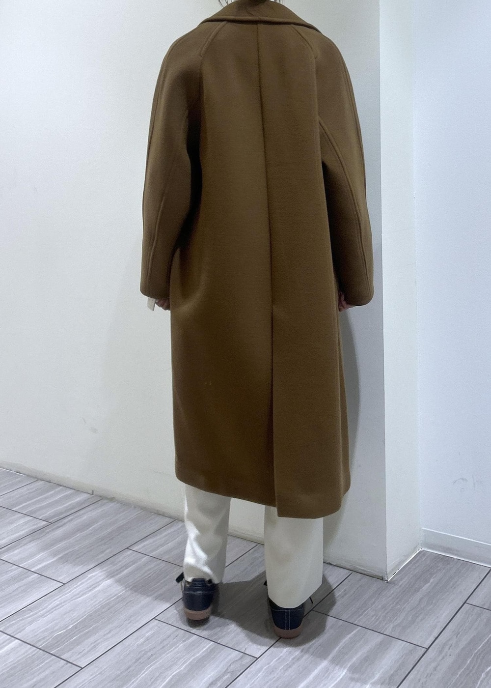 イエロー系のステンカラーコート、ホワイト系のニット/セーター、ホワイト系のその他パンツを着用したレディースの秋コーディネートの4枚目の写真