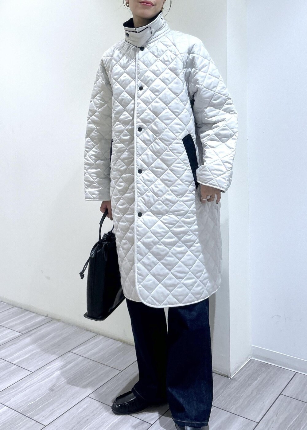 ホワイト系のナイロンジャケット、ブラック系のデニムパンツ、ブラウン系のローファーを着用したレディースの秋コーディネートの5枚目の写真